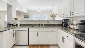 A kitchen with white cabinets, a sink, a dishwasher, and a coffee maker. - Eagles Landing townhome with pool and tennis access, patio & grill (Rehoboth Beach)