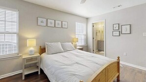 A bedroom with a bed, nightstands, a ceiling fan, and framed artwork on the walls. - Eagles Landing townhome with pool and tennis access, patio & grill (Rehoboth Beach)