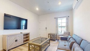 Een woonkamer met een bank, een salontafel, een televisie en een kast.