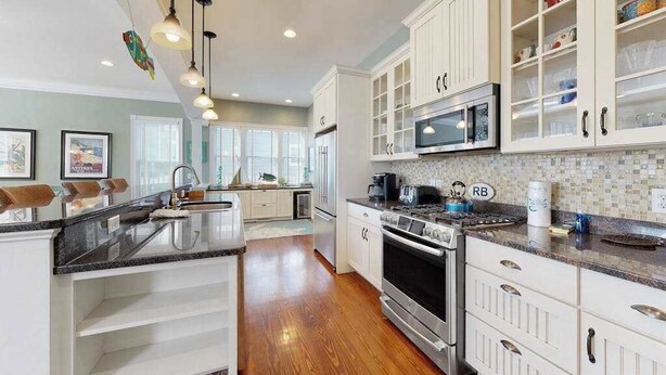 A kitchen with white cabinets, a central island, stainless steel appliances, and pendant lighting. - Elegant house near the ocean with AC, W/D & outdoor space - walk to boardwalk (Rehoboth Beach)