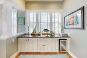 A kitchen with a white cabinetry, a window with blinds, a framed picture on the wall, and a decorative fish on the counter. - Elegant house near the ocean with AC, W/D & outdoor space - walk to boardwalk (Rehoboth Beach)