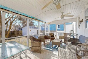 A covered patio area with wicker furniture, a glass table, and ceiling fans. - Spacious dog-friendly house with enclosed porch and yard- perfect for families! (Rehoboth Beach)