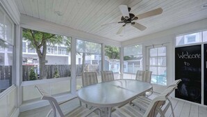 Un patio techado con una mesa, sillas, un ventilador de techo y un letrero que dice 'Bienvenidos'.