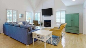 Amplia sala de estar con un sofá azul, una mesa de centro blanca, un mueble verde y una chimenea.
