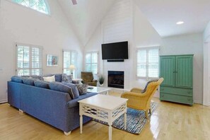 Ein geräumiges Wohnzimmer mit blauem Sofa, weißem Couchtisch, grünem Schrank und Kamin.