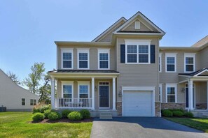 A two-story residential building with a front porch, a garage, and a well-maintained lawn. - Coastal Luxury & Community Charm: Your Rehoboth Beach Retreat (Rehoboth Beach)