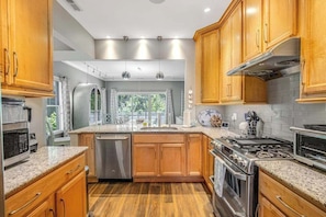 A modern kitchen with wooden cabinets, stainless steel appliances, and a large window. - Oyster Bay Villas with pool, central AC, fast WiFi, & washer/dryer. Dogs ok (Rehoboth Beach)