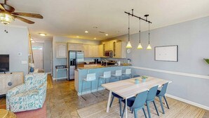 Une cuisine moderne avec un îlot central, des chaises bleu clair et une table à manger.