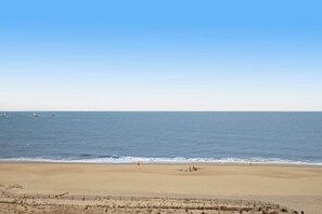 Een strand met een zandstrand, een hek en een heldere lucht.
