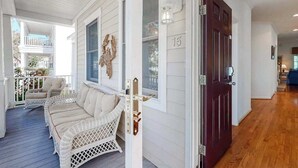 A porch with wicker furniture, a dark wooden door, and a white exterior. - Bear Trap Dunes house w/ fireplace, free WiFi, board games, and tennis court (Ocean View)