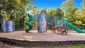Ein Spielplatz mit Klettergerüsten, Rutschen und einem Holzzaun.