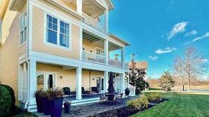 Una casa a due piani con un balcone, un portico coperto e un prato curato.