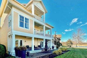 Ein zweistöckiges Haus mit Balkon, überdachter Veranda und gepflegtem Rasen.
