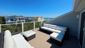 Ein Balkon mit einer weißen Couch, einem kleinen Tisch und einem Rattanaschliessfach.