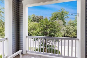 A porch with a white railing, a clear view of trees and a street, and a blue sky. - Sawgrass at White Oak Creek - townhome with AC, pools & gyms (Rehoboth Beach)