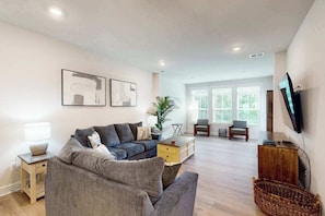 A modern living room with a sofa, a coffee table, a TV, and artwork on the wall. - The Peninsula spacious home w/community pool, hot tub, tennis courts (Millsboro)