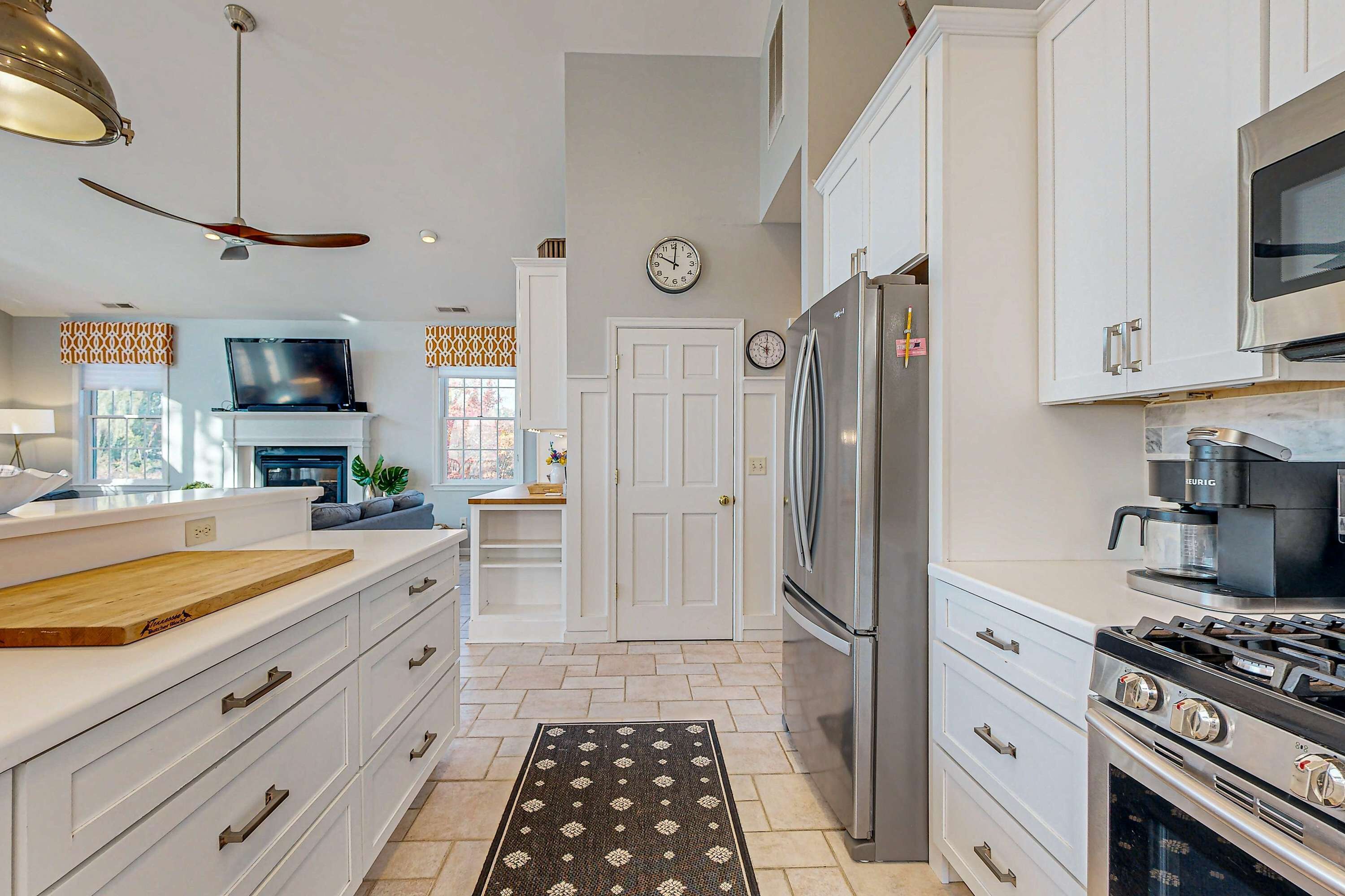 Une cuisine moderne avec des meubles blancs, un réfrigérateur en acier inoxydable, une cuisinière à gaz et un four à micro-ondes.