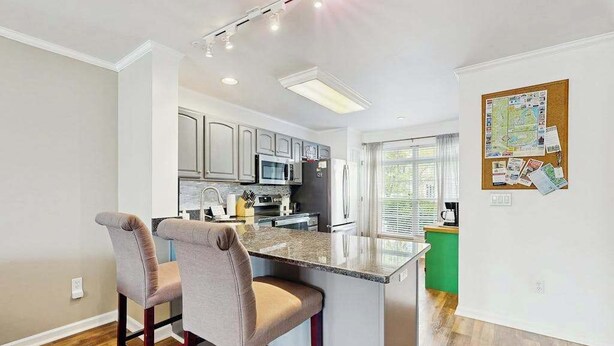 A modern kitchen with a central island, bar stools, and a bulletin board on the wall. - Taramino Spacious Townhouse w/shared pool, W/D & free WIFI (Lewes)