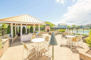 Une terrasse extérieure dotée d’un belvédère, de coins salon et d’une piscine en arrière-plan.