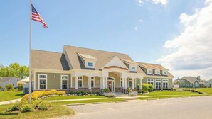 A two-story building with a central entrance, a flagpole with an American flag, and a parking lot. - Lovely, dog-friendly townhouse near the beach with a pool & washer/dryer (Rehoboth Beach)
