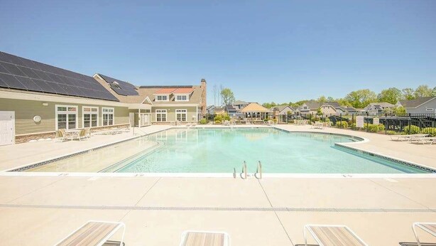 A swimming pool with lounge chairs, a building with solar panels, and a clear sky. - Lovely, dog-friendly townhouse near the beach with a pool & washer/dryer (Rehoboth Beach)