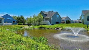 A residential area with houses, a pond, and a fountain. - Grande at Canal Pointe condo with pools, tennis, gym, & private balcony (Rehoboth Beach)
