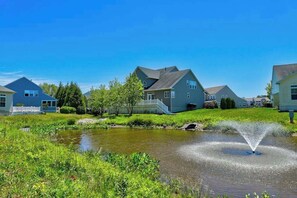 A residential area with houses, a pond, and a fountain. - Grande at Canal Pointe condo with pools, tennis, gym, & private balcony (Rehoboth Beach)