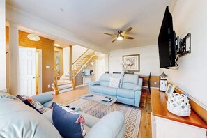 A living room with a blue sofa, a coffee table, and a staircase leading to another room. - Dog-friendly Villages of Five Points townhouse with pool, tennis, gym, grill (Lewes)