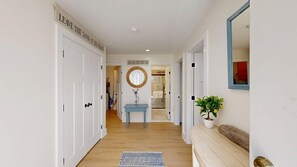 A hallway with white doors, a blue table, a mirror, and a potted plant. - Town of Dewey Beach condo w/deck, balcony, walk to beach, close to restaurants (Dewey Beach)