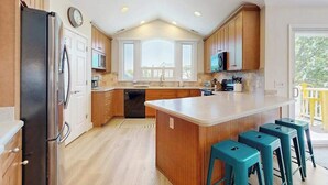 Eine Küche mit Holzausstattung, einer zentralen Kochinsel mit Sitzgelegenheiten, einem Kühlschrank und einer Mikrowelle.