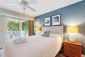 A bedroom with a bed, bedside tables, a ceiling fan, and framed pictures on the wall. - Dog-friendly home 3.5 blocks to beach w/private hot tub, balconies, firepit, AC (Rehoboth Beach)