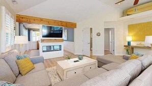 Ein modernes Wohnzimmer mit Sofa, Couchtisch, Fernseher und Deckenventilator.