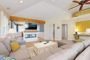 A modern living room with a sofa, coffee table, TV, and ceiling fan. - Dog-friendly home 3.5 blocks to beach w/private hot tub, balconies, firepit, AC (Rehoboth Beach)
