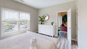 Une chambre à coucher avec un grand lit, une commode, un miroir et une plante en pot.