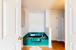 A hallway with a teal bathtub, white doors, and wooden flooring. - Rehoboth Beach home near beach & boardwalk with grill, streaming, & W/D (Rehoboth Beach)