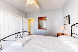 A bedroom with a bed, a nightstand, a lamp, a mirror, and a door. - Stunning Condo- Pool and Hot Tub- Convenient Beach Access! (Rehoboth Beach)