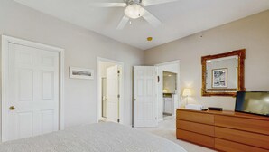 Ein Schlafzimmer mit Bett, Kommode, Deckenventilator und Spiegel.
