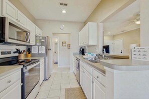 A modern kitchen with white cabinets, stainless steel appliances, and a central island.