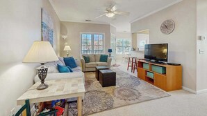 Ein Wohnzimmer mit Sofa, Couchtisch, TV-Schrank und Deckenventilator.