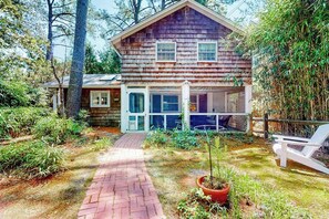 A wooden house with a brick pathway leading to the entrance, surrounded by greenery. - Town of Rehoboth Beach home near beach, tennis courts, grill, patio, W/D, WiFi (Rehoboth Beach)