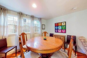 A dining room with a round wooden table, four chairs, a chandelier, and a wall with framed pictures. - Town of Rehoboth Beach home near beach, tennis courts, grill, patio, W/D, WiFi (Rehoboth Beach)
