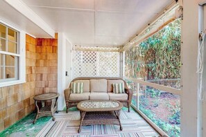 A covered balcony with a wicker sofa, a small round table, and a patterned rug. - Town of Rehoboth Beach home near beach, tennis courts, grill, patio, W/D, WiFi (Rehoboth Beach)