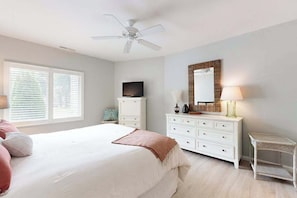 A bedroom with a bed, a dresser, a television, a ceiling fan, and a window with blinds. - Spring Lake Condo with patio, free WIFI, W/D, shared pool (Rehoboth Beach)