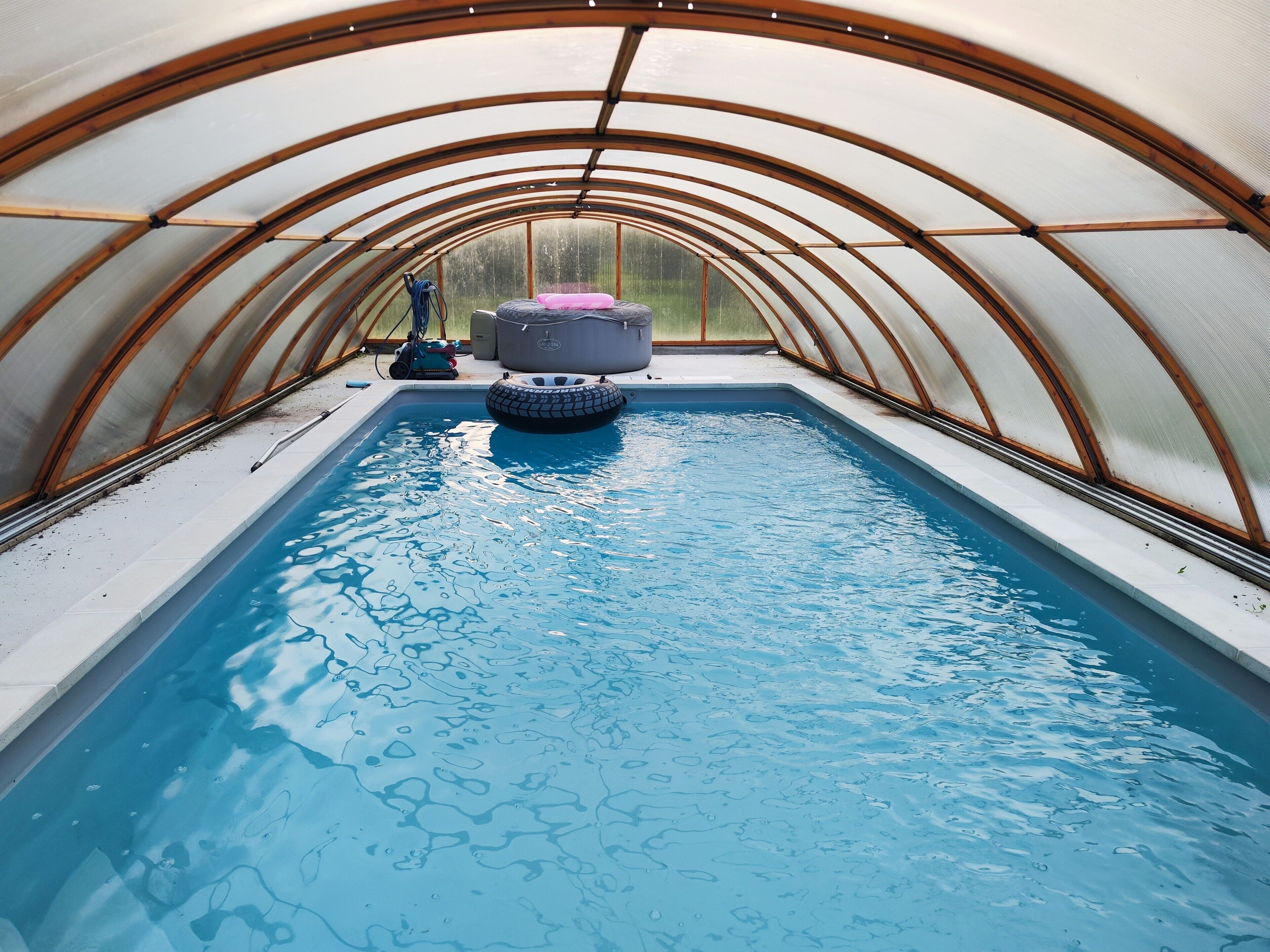 A swimming pool with a rubber ring in the center, surrounded by a covered area with a curved roof structure.