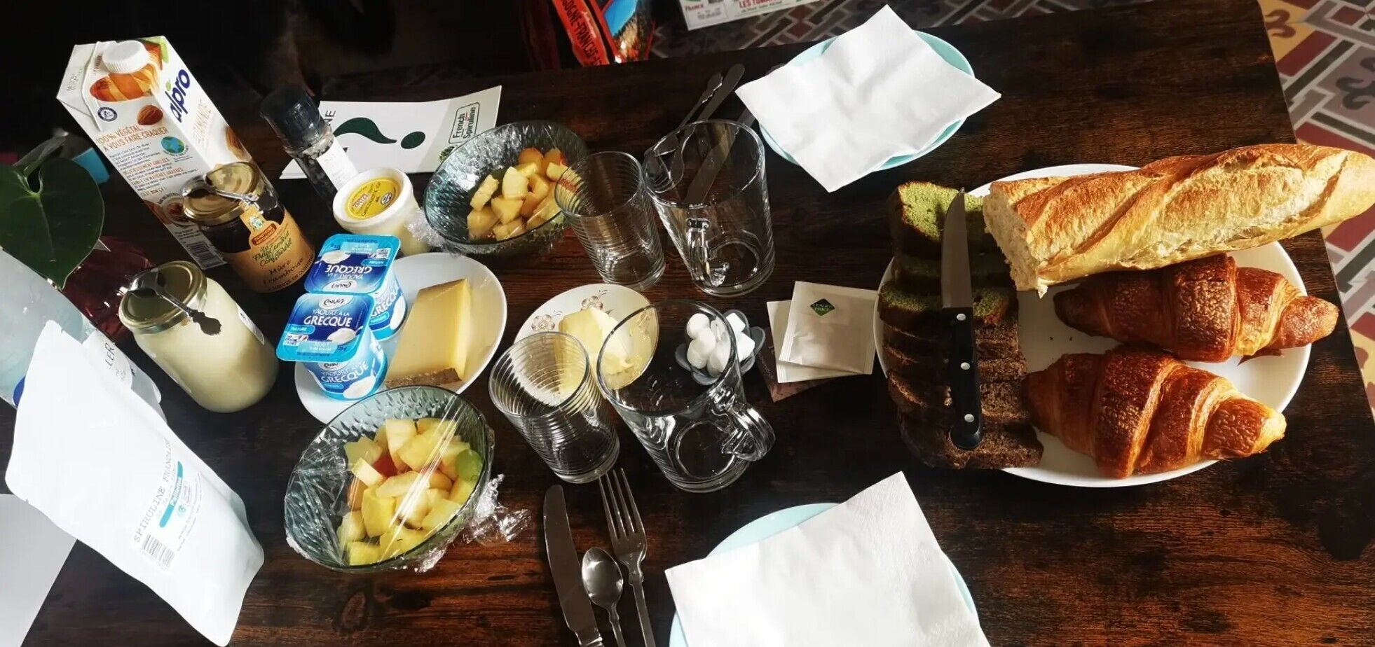 Ein Tisch mit Speisen, einem Messer und einer Platte Croissants.