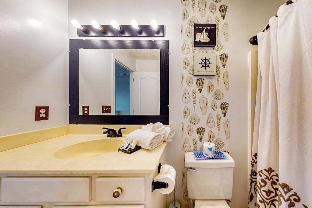 Een badkamer met wastafel, spiegel, toilet en douchegordijn.