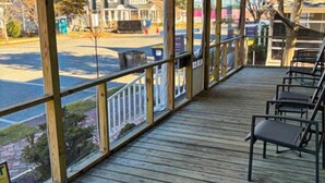 A covered outdoor seating area with wooden flooring and metal railings, overlooking a street. - Town of Rehoboth Beach dog-friendly house close to beach & restaurants (Rehoboth Beach)