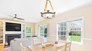 Un salon spacieux avec une cheminée, un téléviseur, une table à manger et de grandes fenêtres.