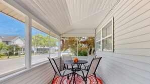 A covered porch with a table and chairs, large windows, and a view of the street. - Dog-friendly Rehoboth Beach gem steps from beach & boardwalk with fast WiFi (Rehoboth Beach)