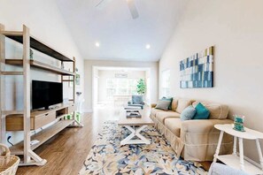 A living room with a TV, sofa, coffee table, and a patterned rug. - Dog-friendly townhome with pool, central AC, & W/D - only 1.5 miles the beach (Rehoboth Beach)